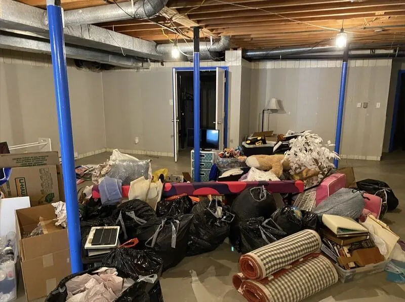 A basement packed with furniture, boxes and bags before a cleanout