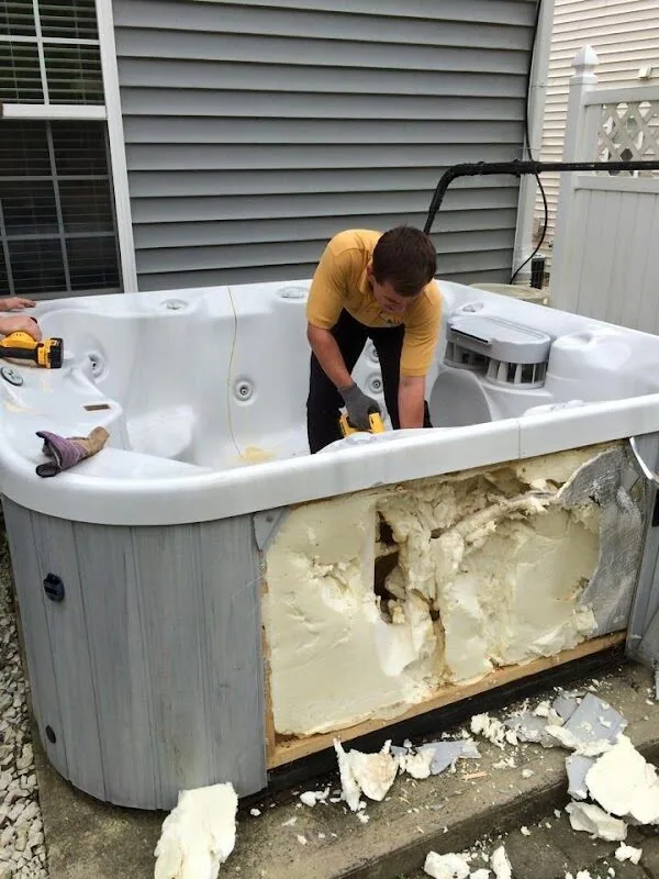 A Junk Doctors crew member cutting an old hot tub into sections