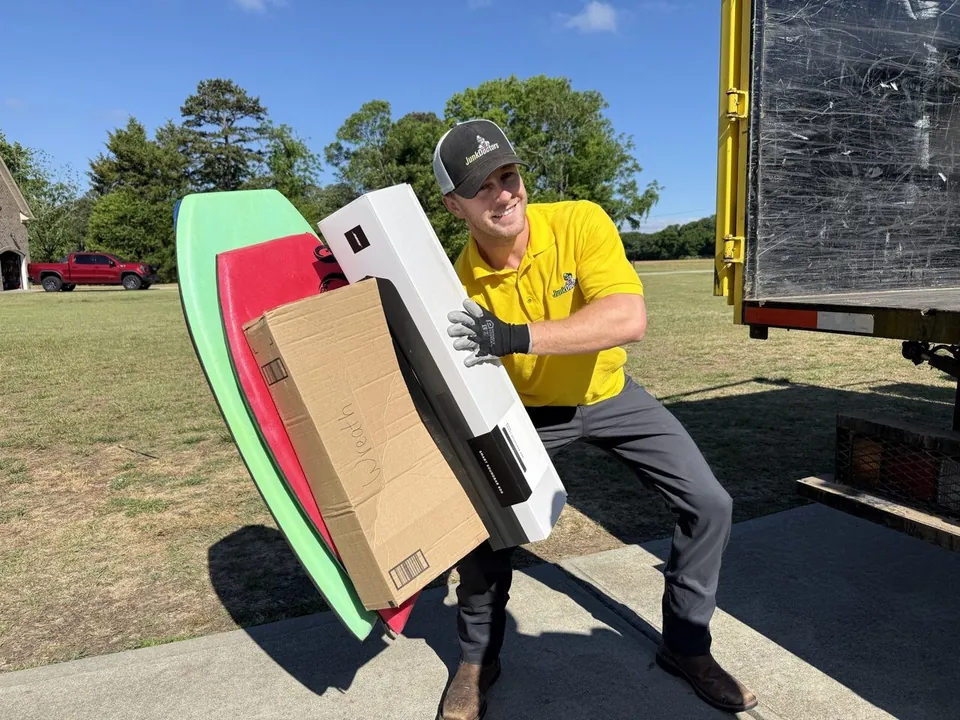 A Junk Doctors crew member carrying boxes and boards to the truck